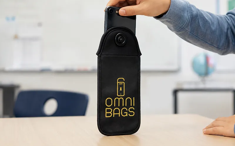 Schüler legt sein Smartphone in die OMNI-Bag